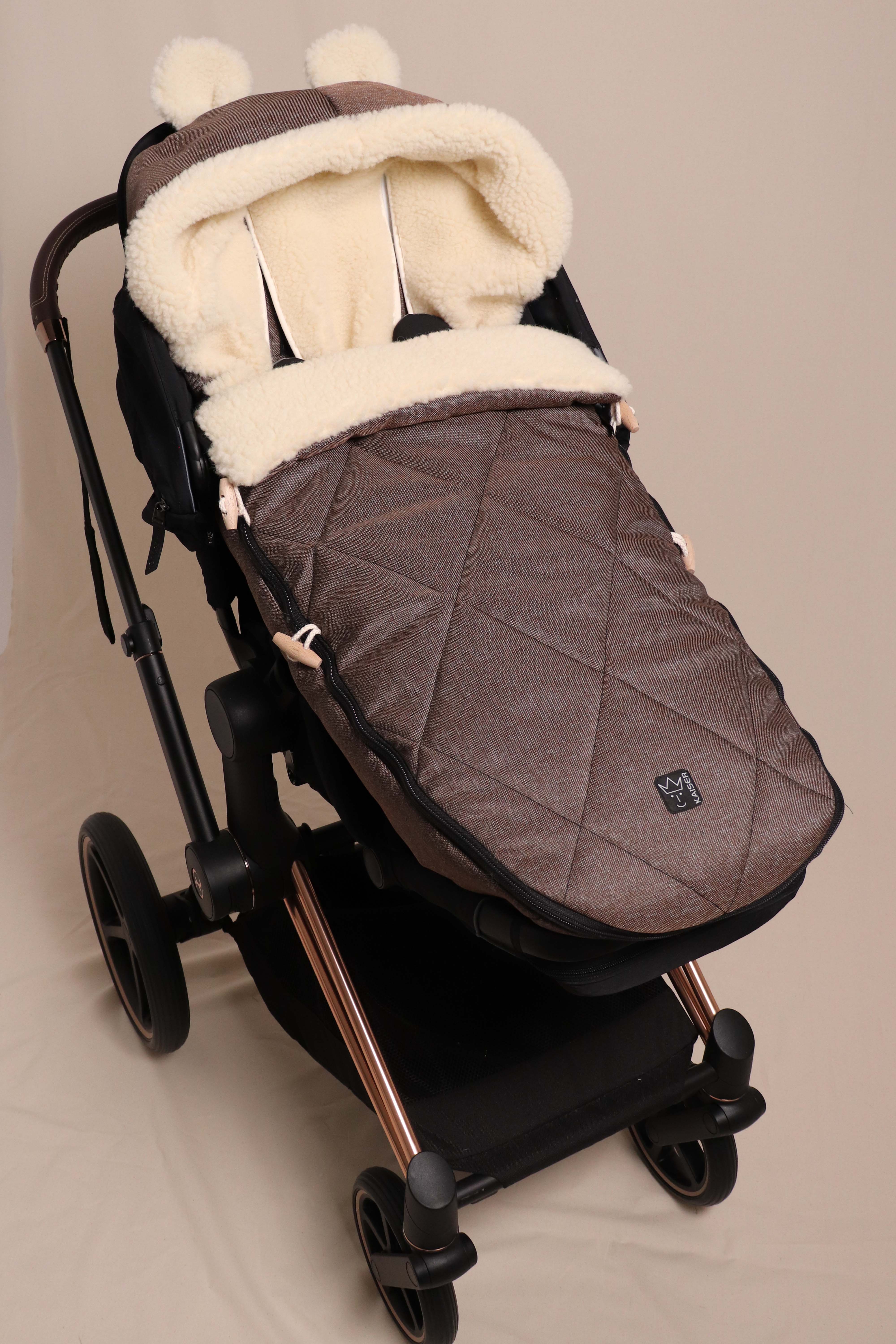 Geschlossener Fußsack in braun mit Schafwolle-Innenfutter ist in einem Kinderwagen eingesetzt
