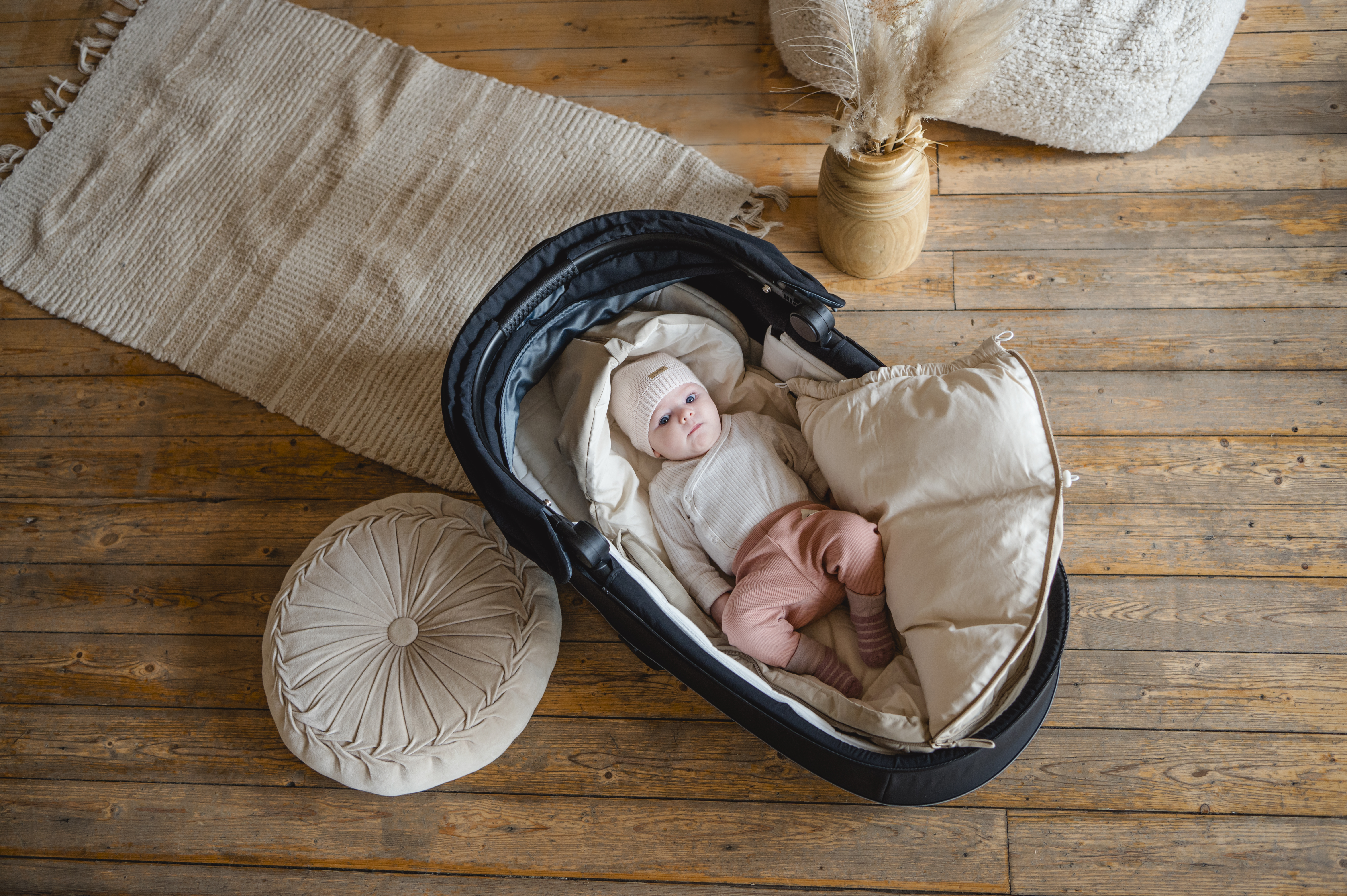 Baby liegt entspannt im offenen LITTLE DOWNY Babyschalen-Fußsack in der Farbe sand in schwarzer Babyschale