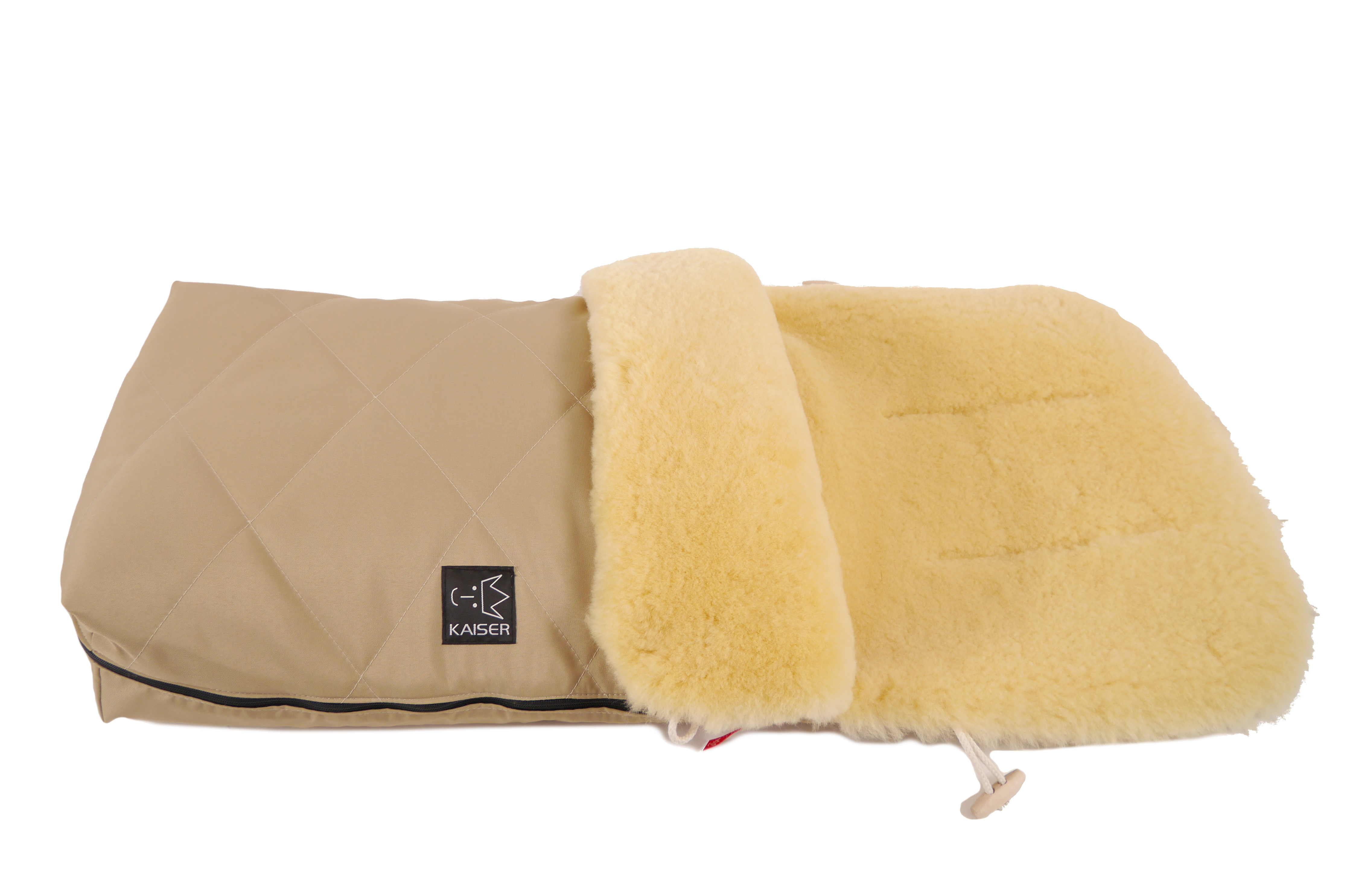 Fußsack mit dem Lammfell-Innenfutter in der Farbe sand und schwarzem „Kaiser“-Logo auf der Vorderseite liegt horizontal