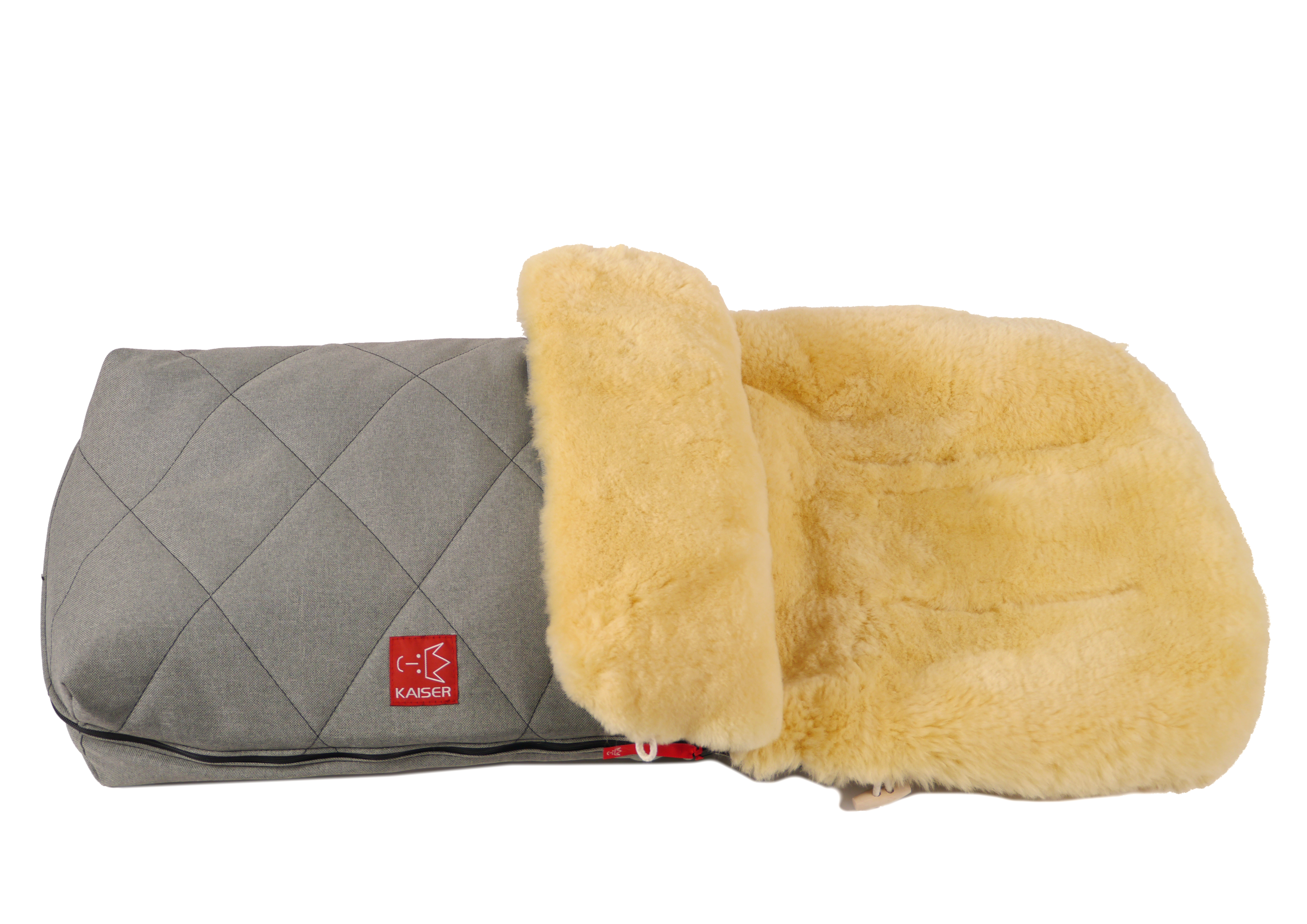 Fußsack mit dem Lammfell-Innenfutter in der Farbe grey melange und rotem „Kaiser“-Logo auf der Vorderseite liegt horizontal