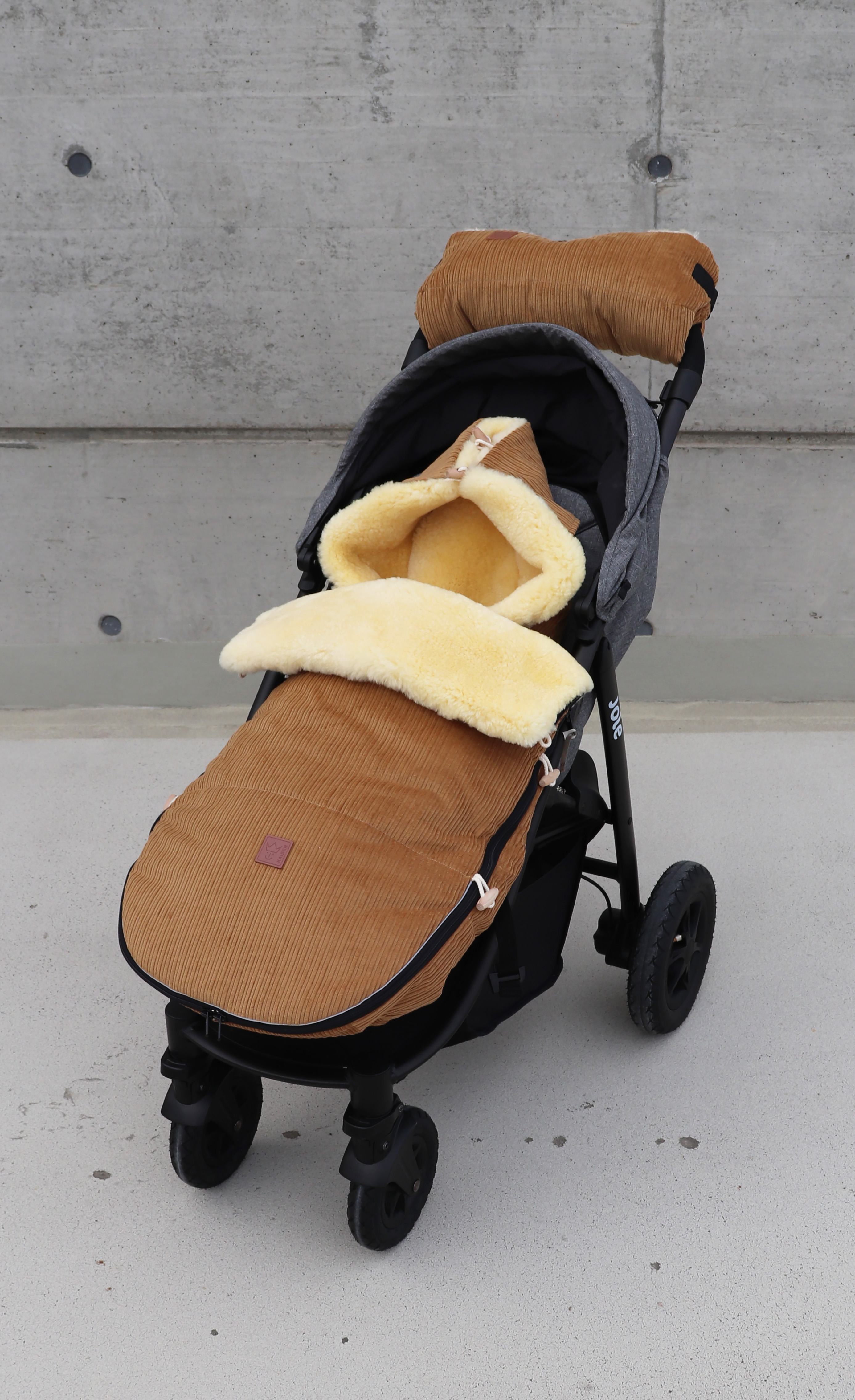Fußsack mit dem Lammfell-Innenfutter in der Farbe camel ist in einem Kinderwagen eingesetzt