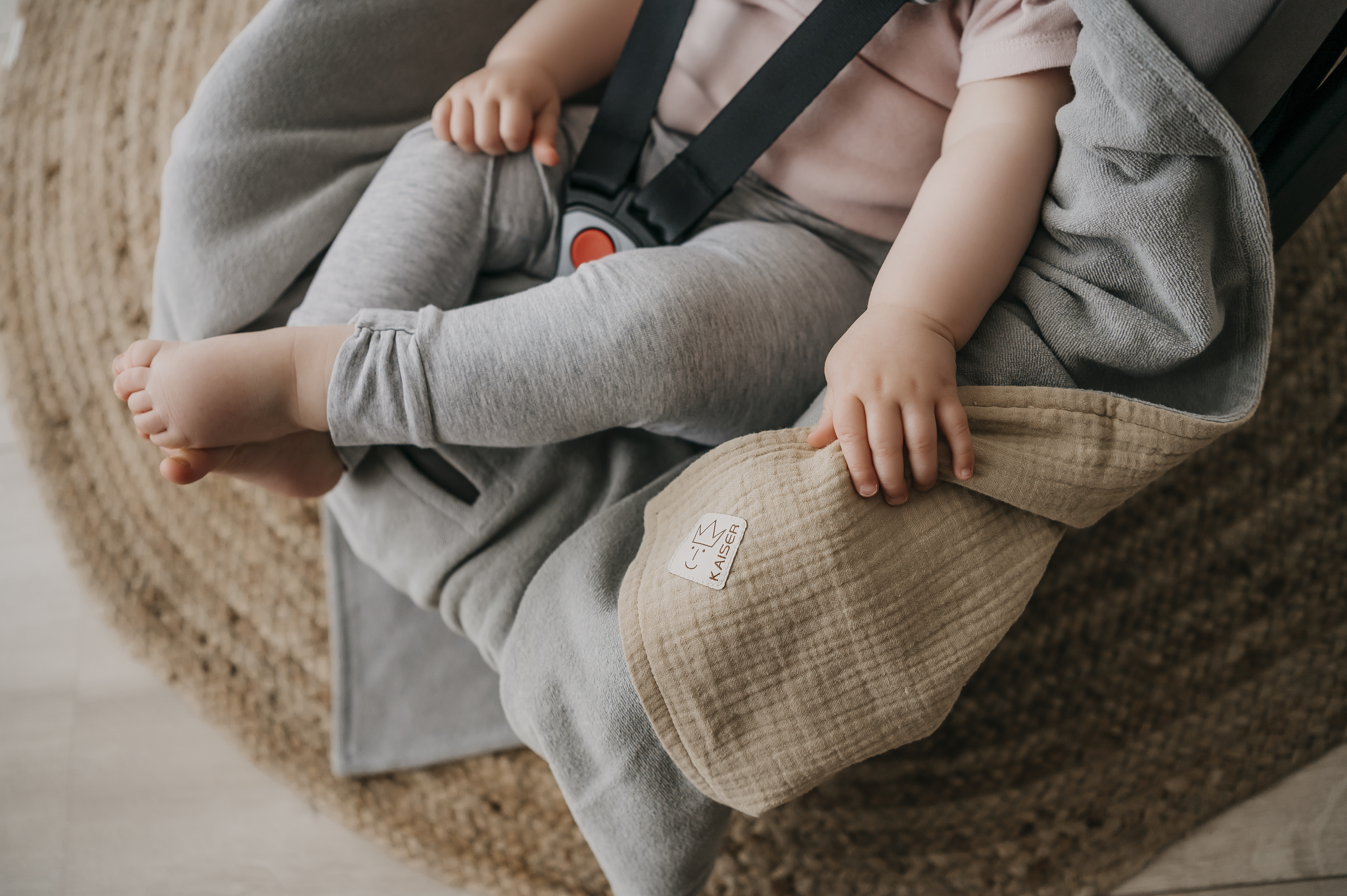Baby sitzt in Babyschale mit SUNNY Einschlagdecke von Kaiser, Detailansicht Hände und Füße