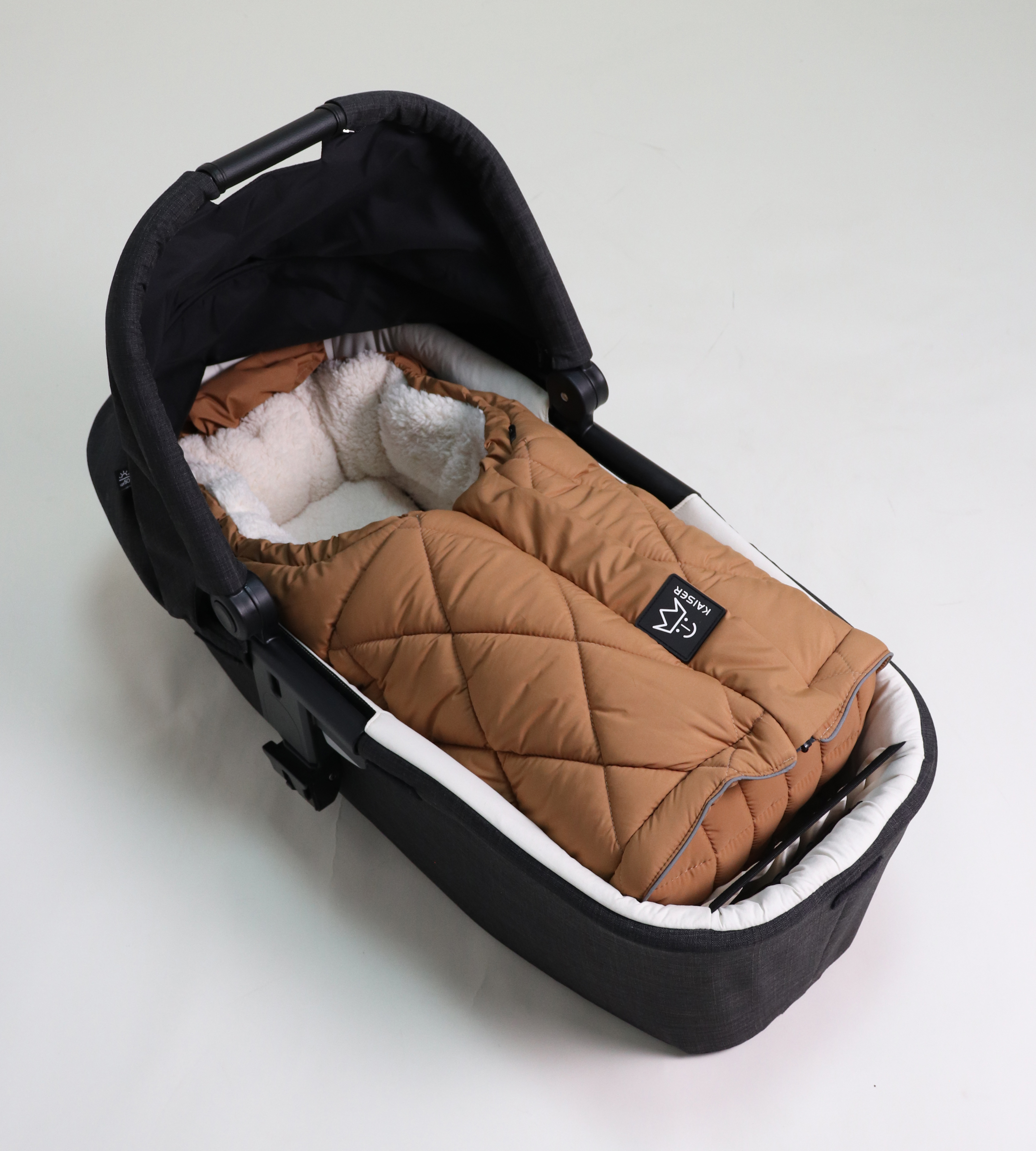 MOONY 2in1, Thermo Universal Fußsack Geschlossener Fußsack mit einem Sherpa-Futter in der Farbe camel liegt in einer Babyschale