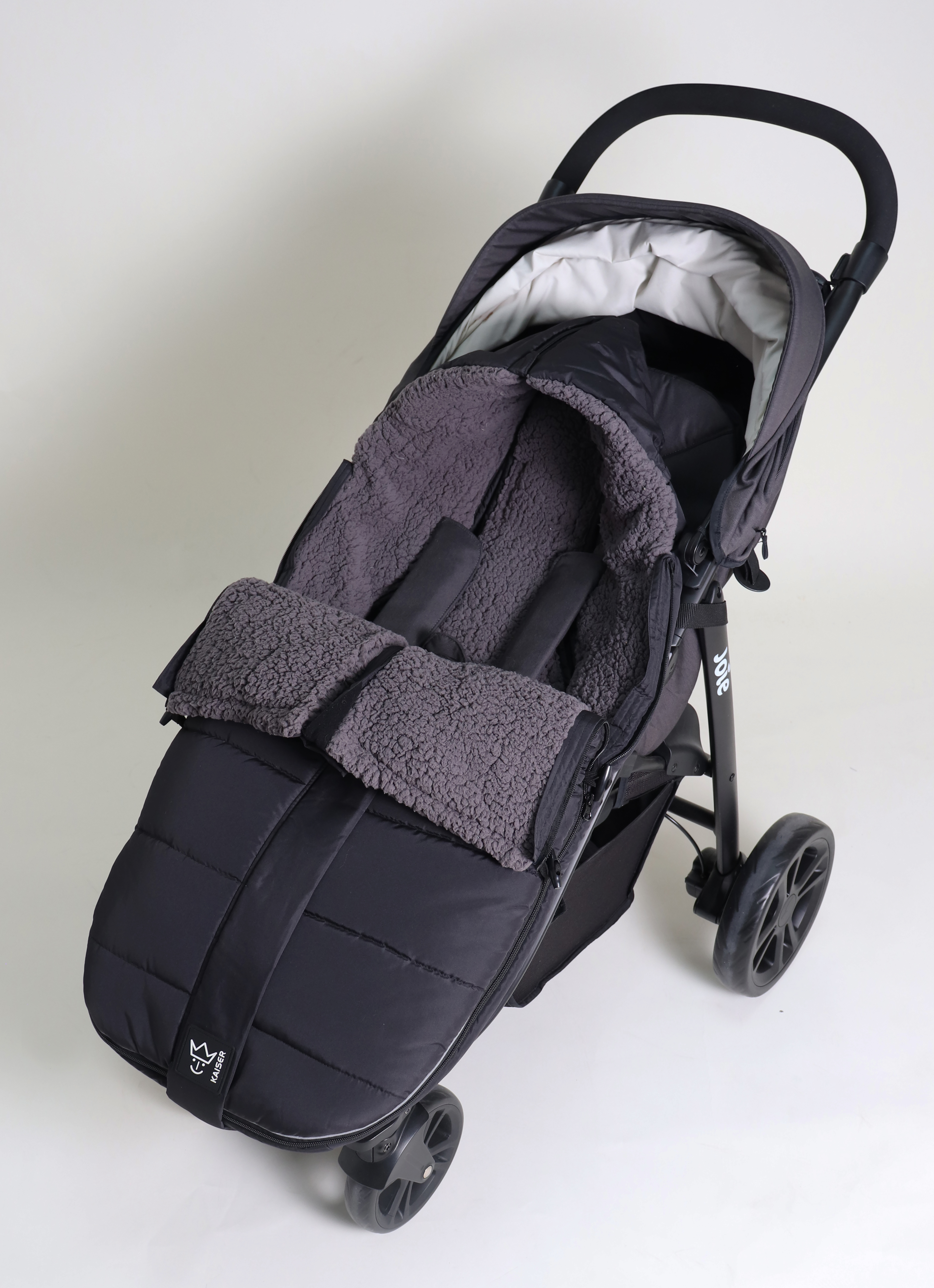 Geschlossener Fußsack mit einem Sherpa-Futter in der Farbe black ist in einem Kinderwagen eingesetzt