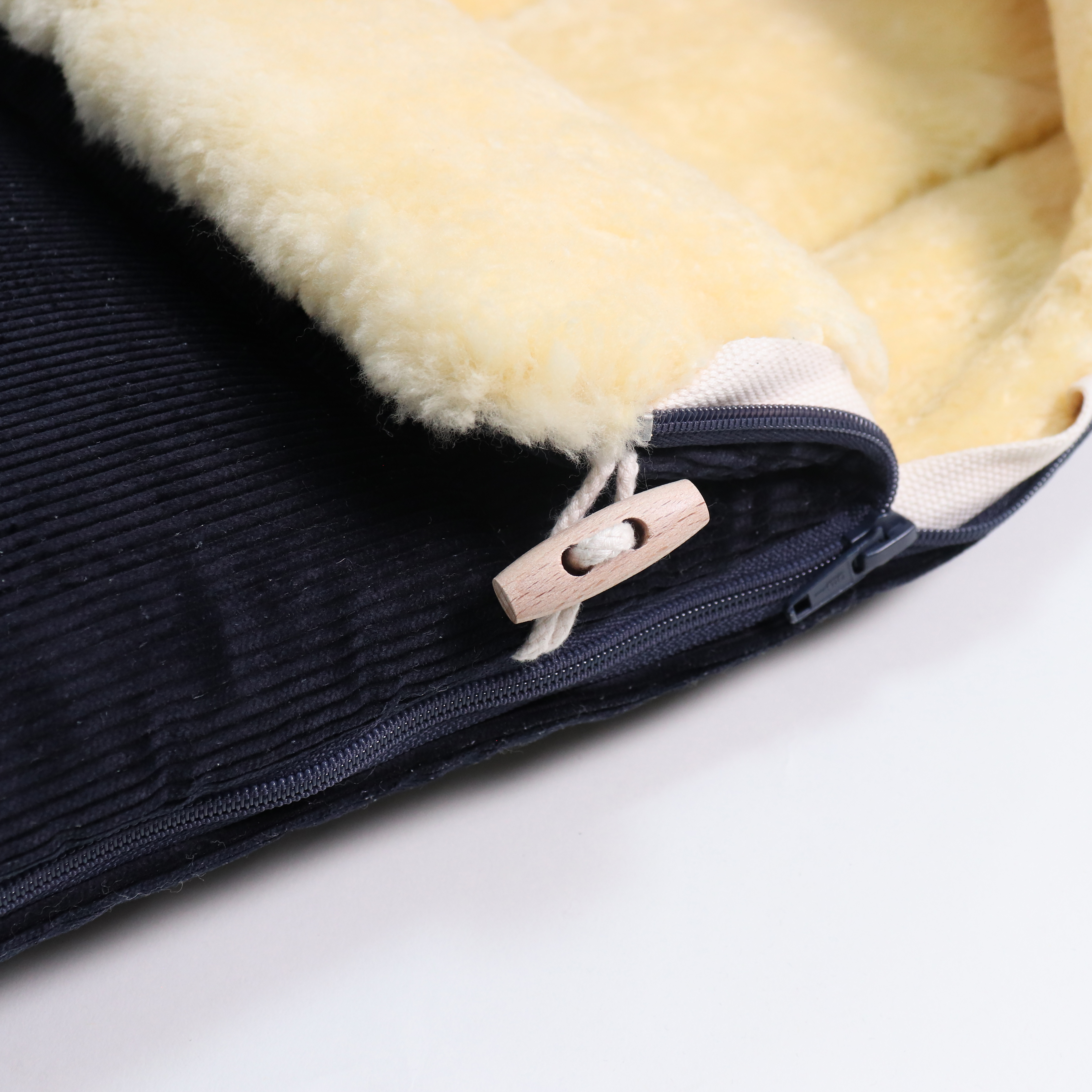 Detailaufnahme Reißverschluss und Holzknopf am FILIA CORD Babyschalen Fußsack mit Lammfell in der Farbe dark blue sea