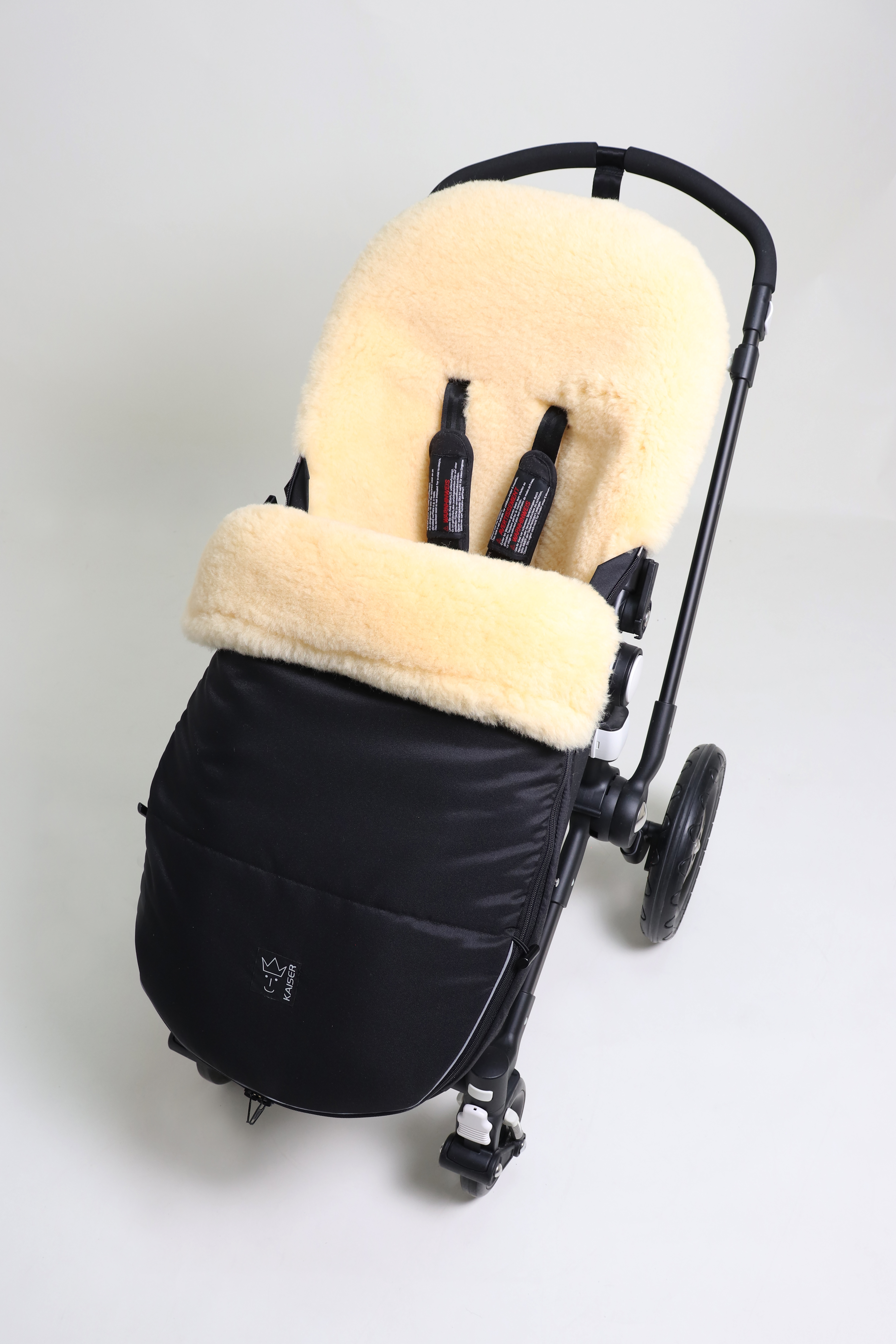 Fußsack mit dem Lammfell-Innenfutter in black in einem Kinderwagen eingesetzt