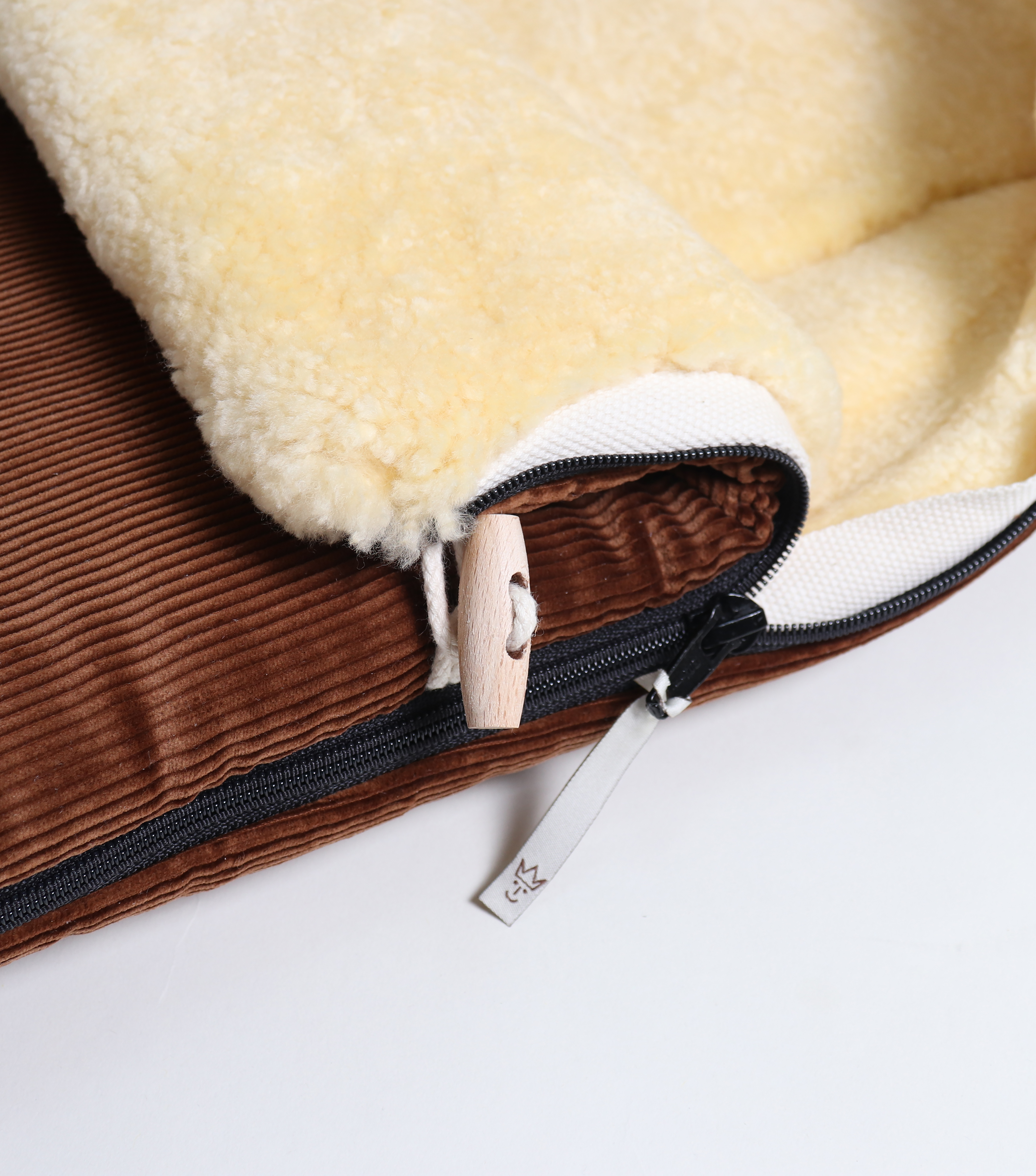 Detailaufnahme Reißverschluss und Holzknopf am FILIA CORD Babyschalen Fußsack mit Lammfell in der Farbe brown
