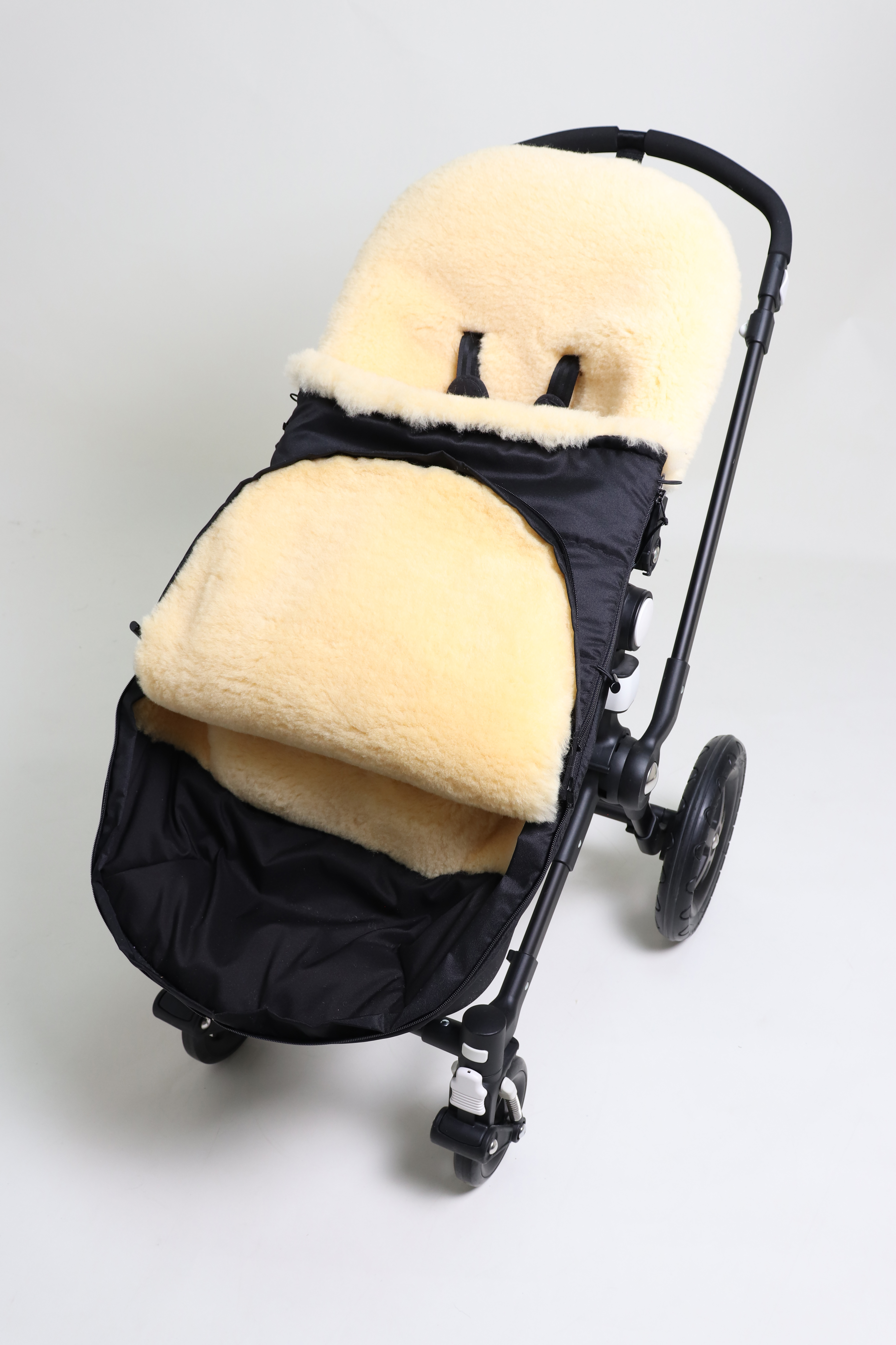 Fußsack mit dem Lammfell-Innenfutter in black in einem Kinderwagen eingesetzt