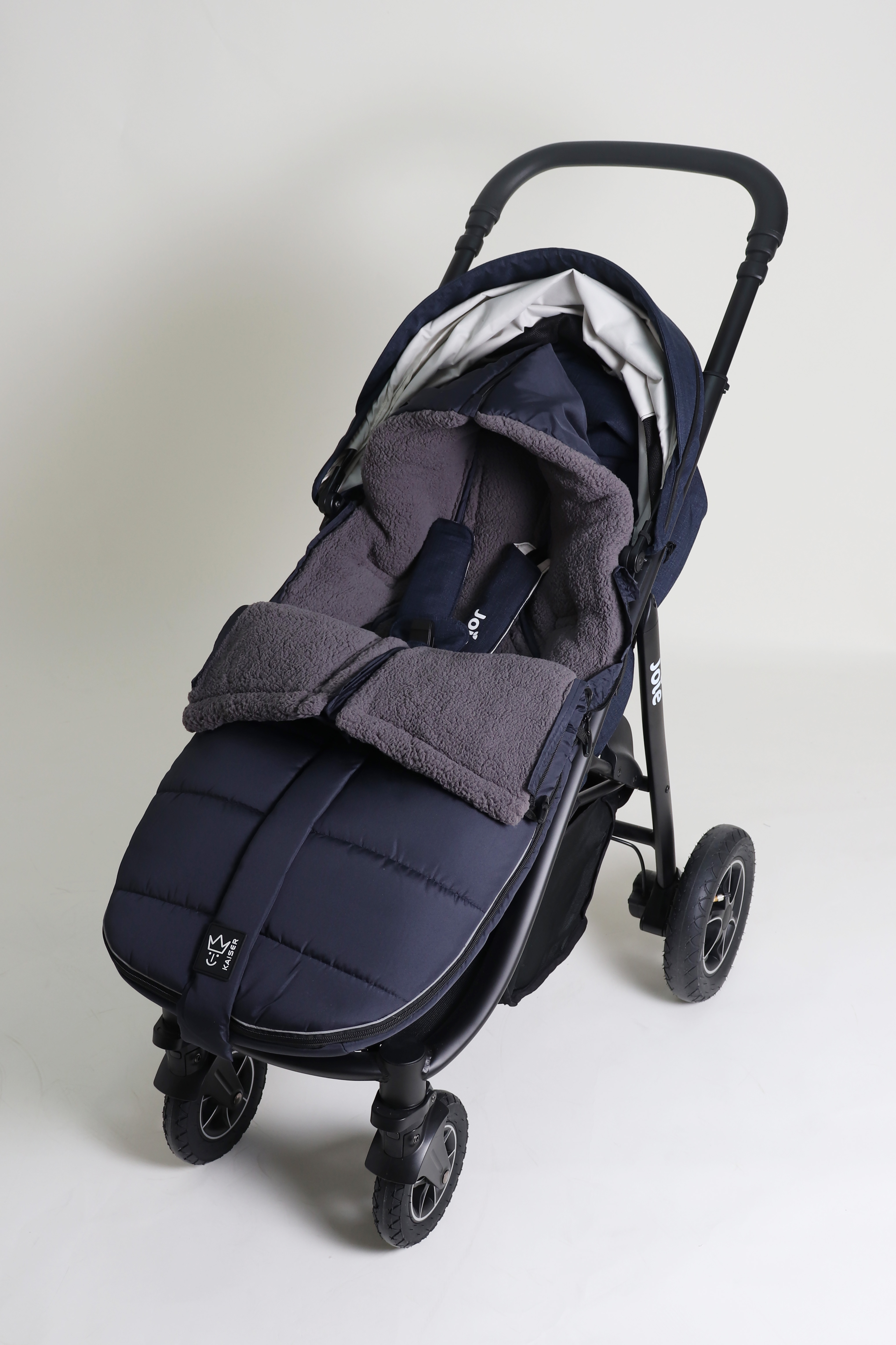 Geschlossener Fußsack mit einem Sherpa-Futter in der Farbe navy liegt ist in einem Kinderwagen eingesetzt