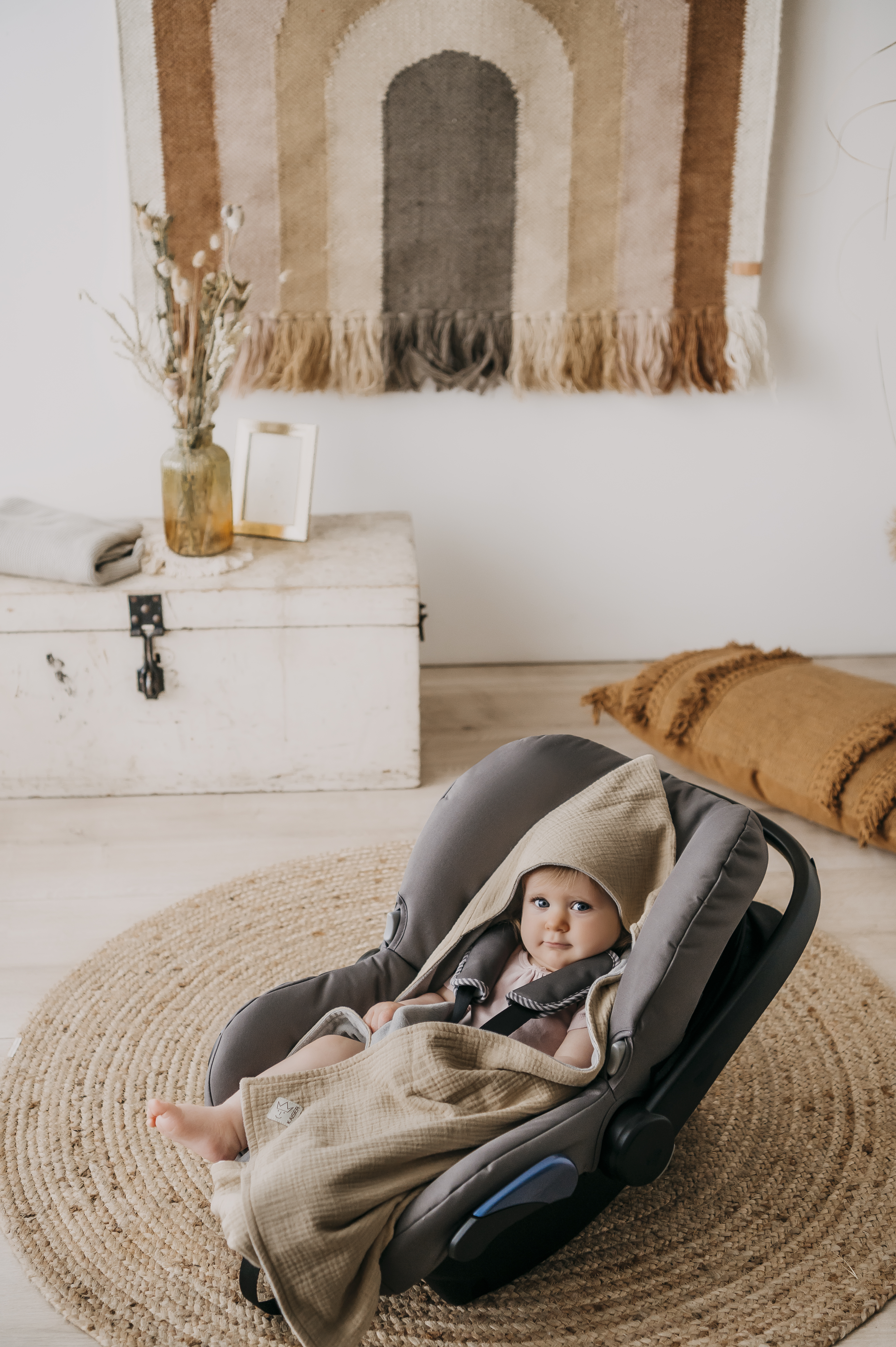 Baby in Babyschale mit SUNNY Einschlagdecke von Kaiser, gemütlich im Wohnzimmer