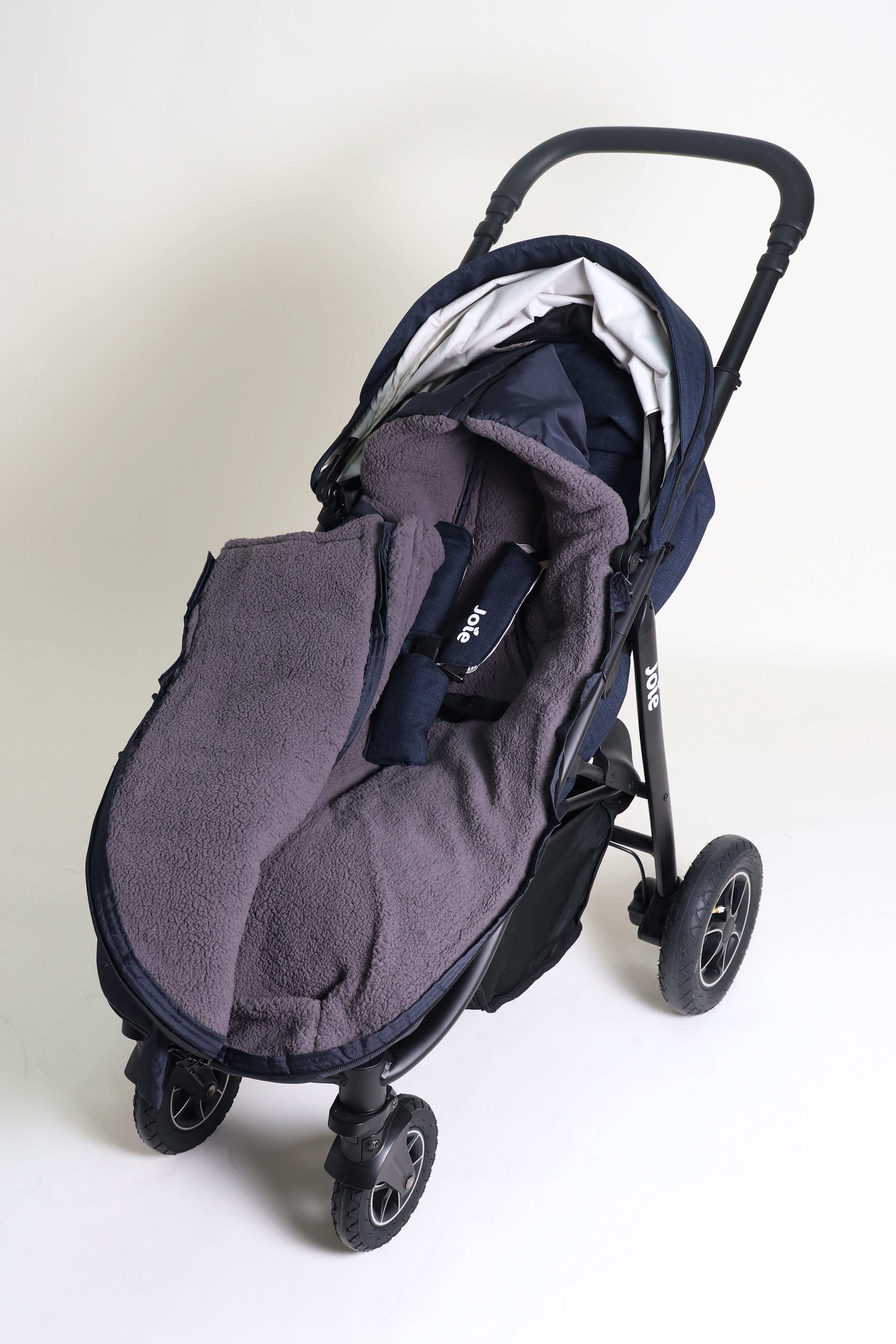 Geschlossener Fußsack mit einem Sherpa-Futter in der Farbe navy liegt ist in einem Kinderwagen eingesetzt