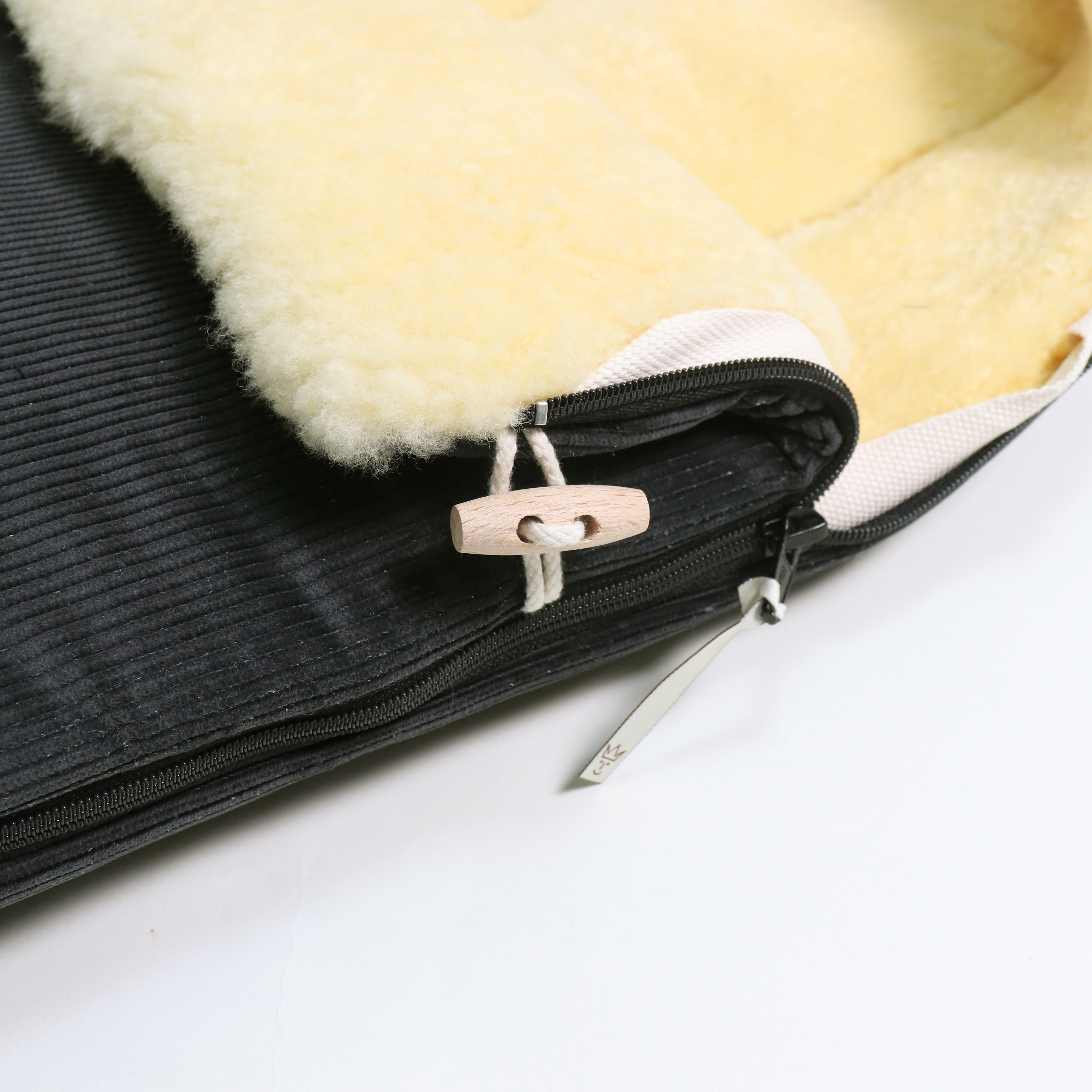 Detailaufnahme Reißverschluss und Holzknopf am FILIA CORD Babyschalen Fußsack mit Lammfell in der Farbe dark grey