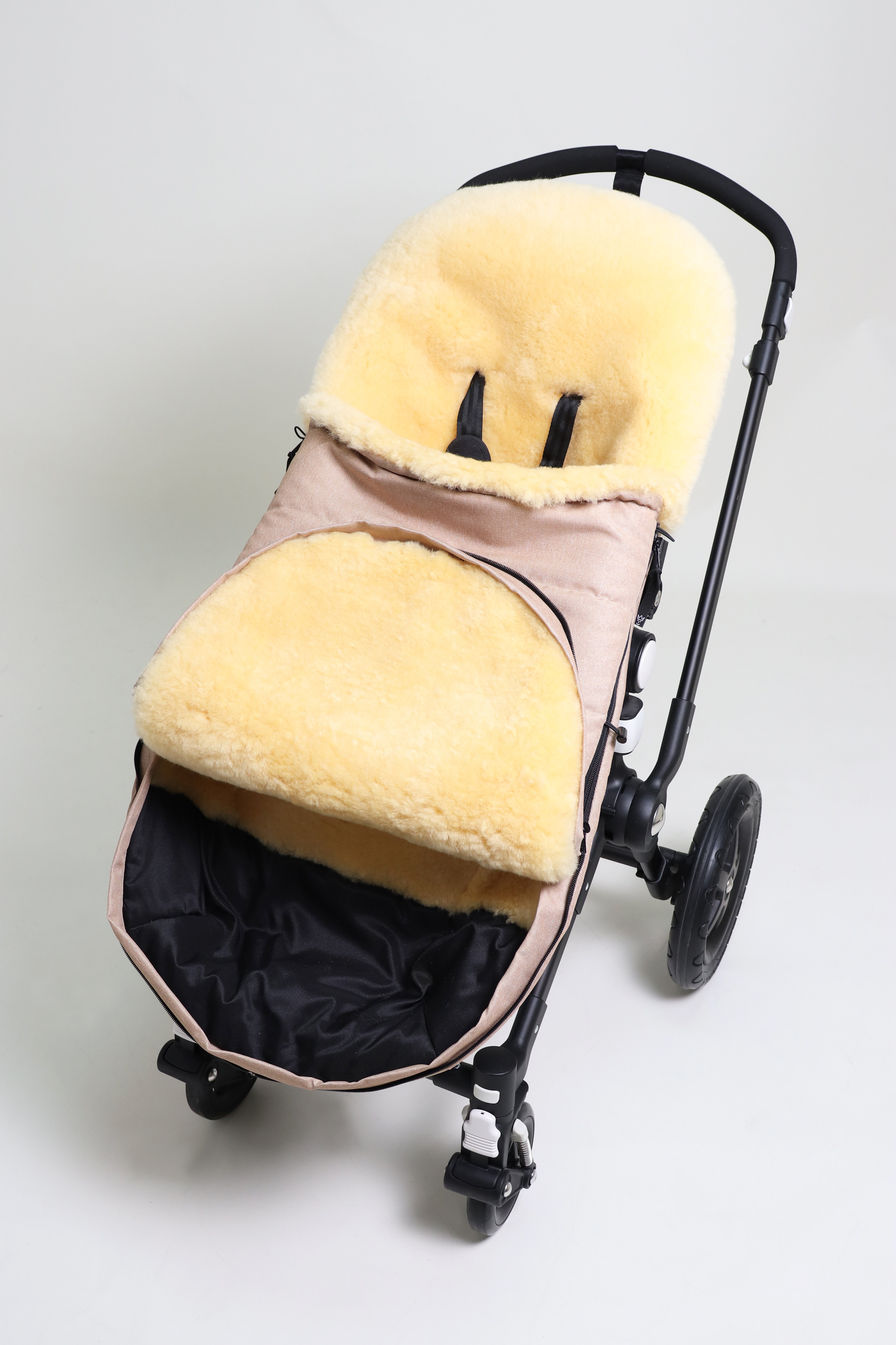 Fußsack mit dem Lammfell-Innenfutter in sand-melange in einem Kinderwagen eingesetzt