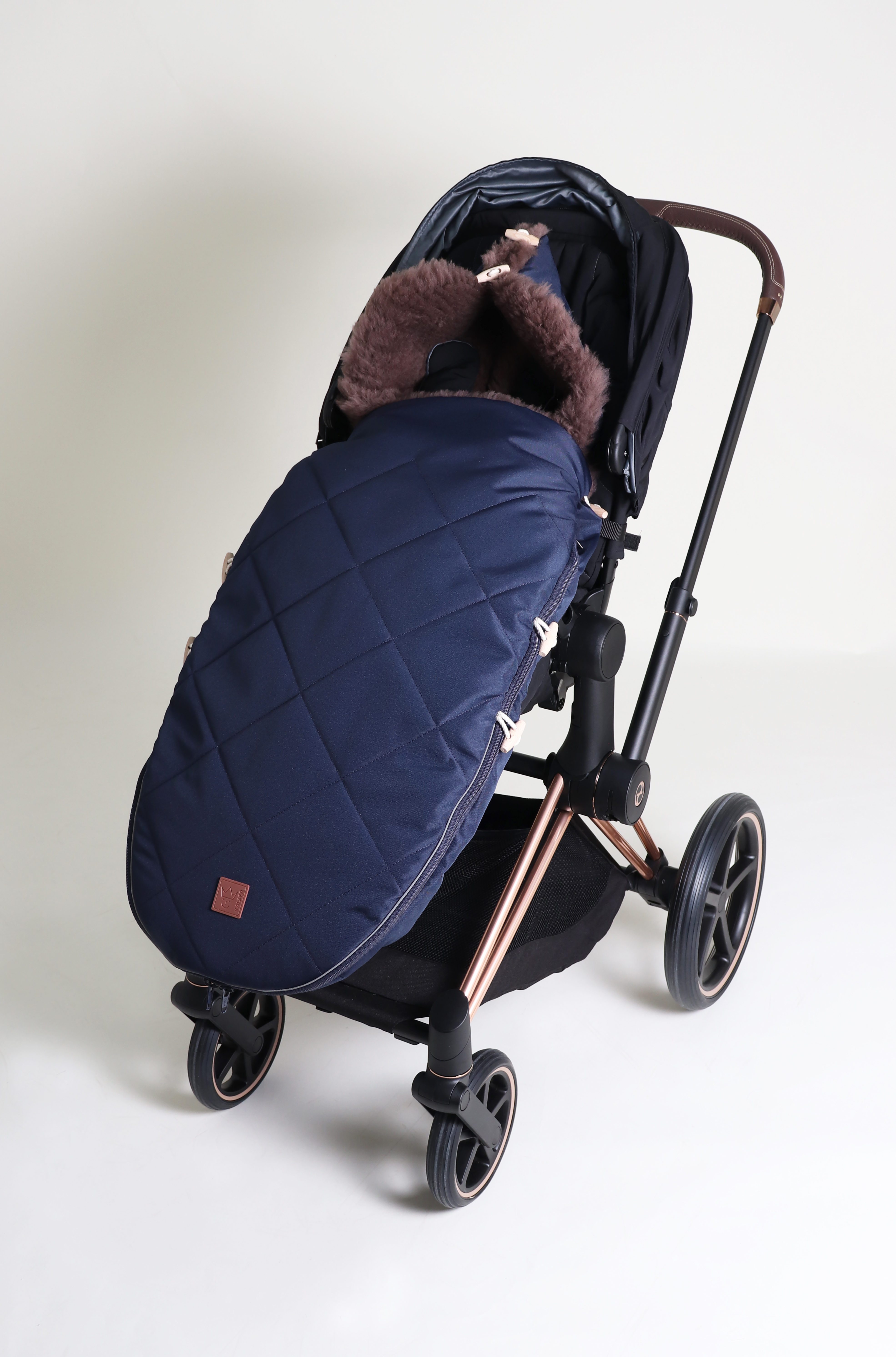 Fußsack mit beigem Lammfell-Innenfutter in der Farbe navy ist in einem Kinderwagen eingesetzt