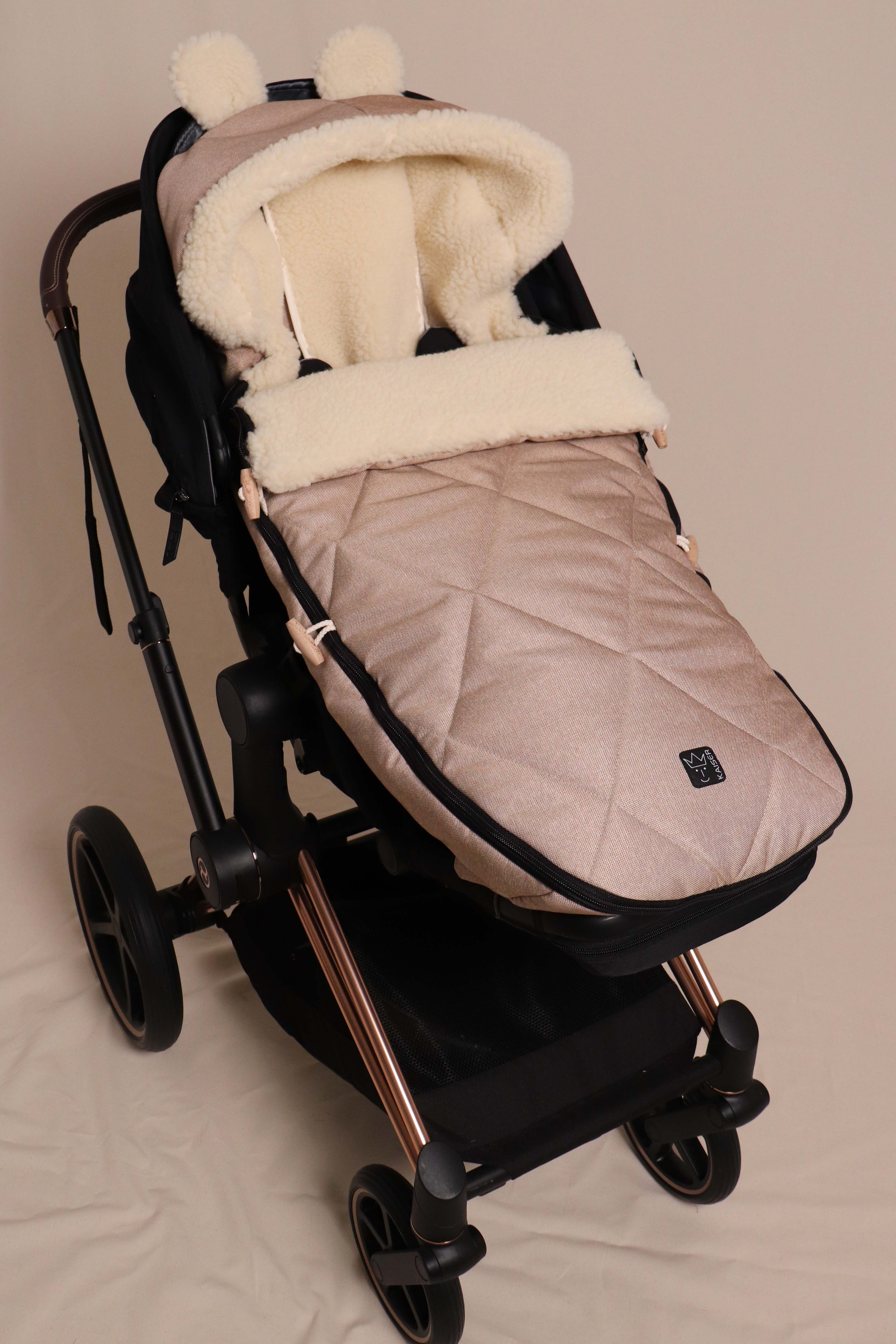 Geschlossener Fußsack in sand mit Schafwolle-Innenfutter ist in einem Kinderwagen eingesetzt