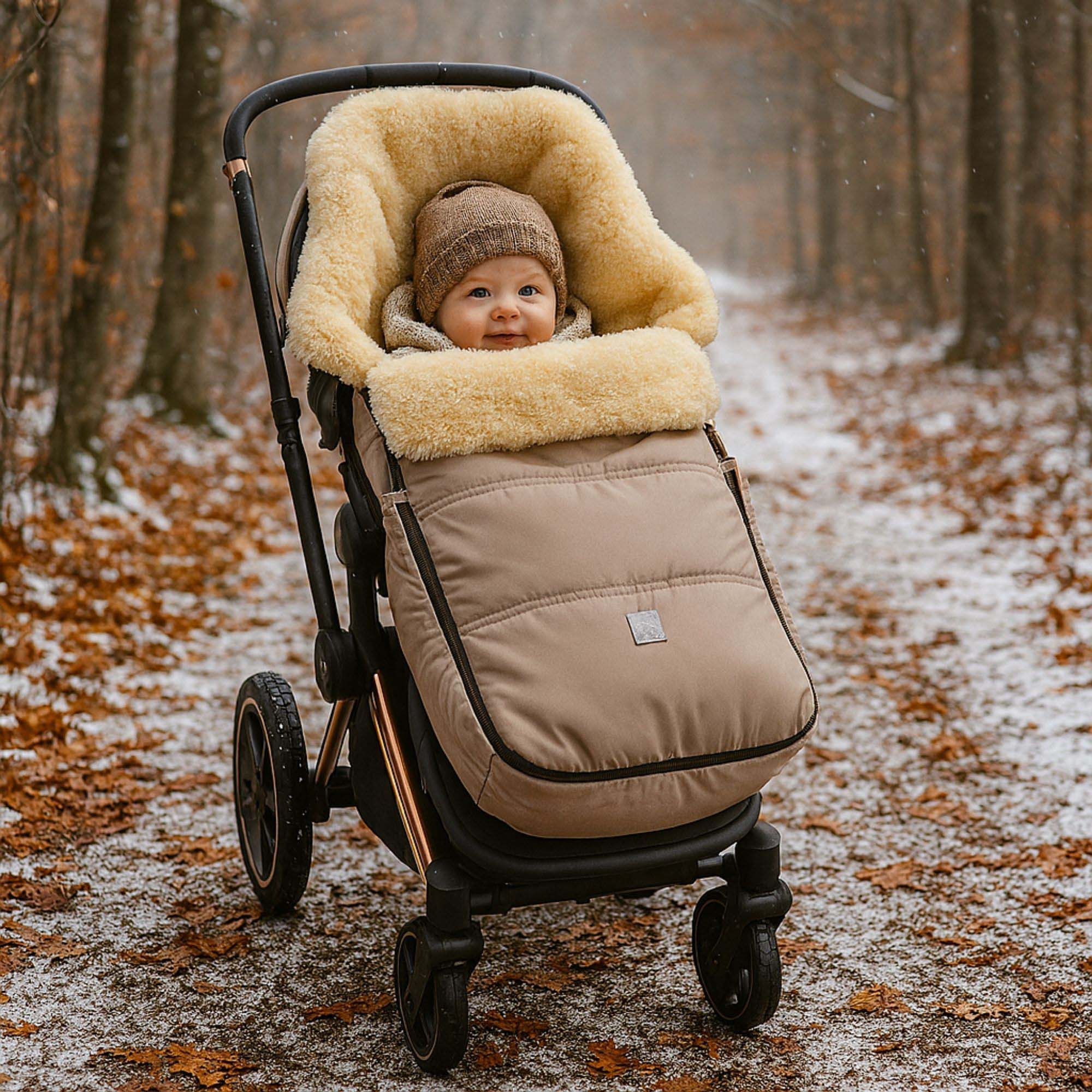 Baby sitzt im Lammfellfußsack im Kinderwagen auf verschneitem Waldweg, warm eingekuschelt