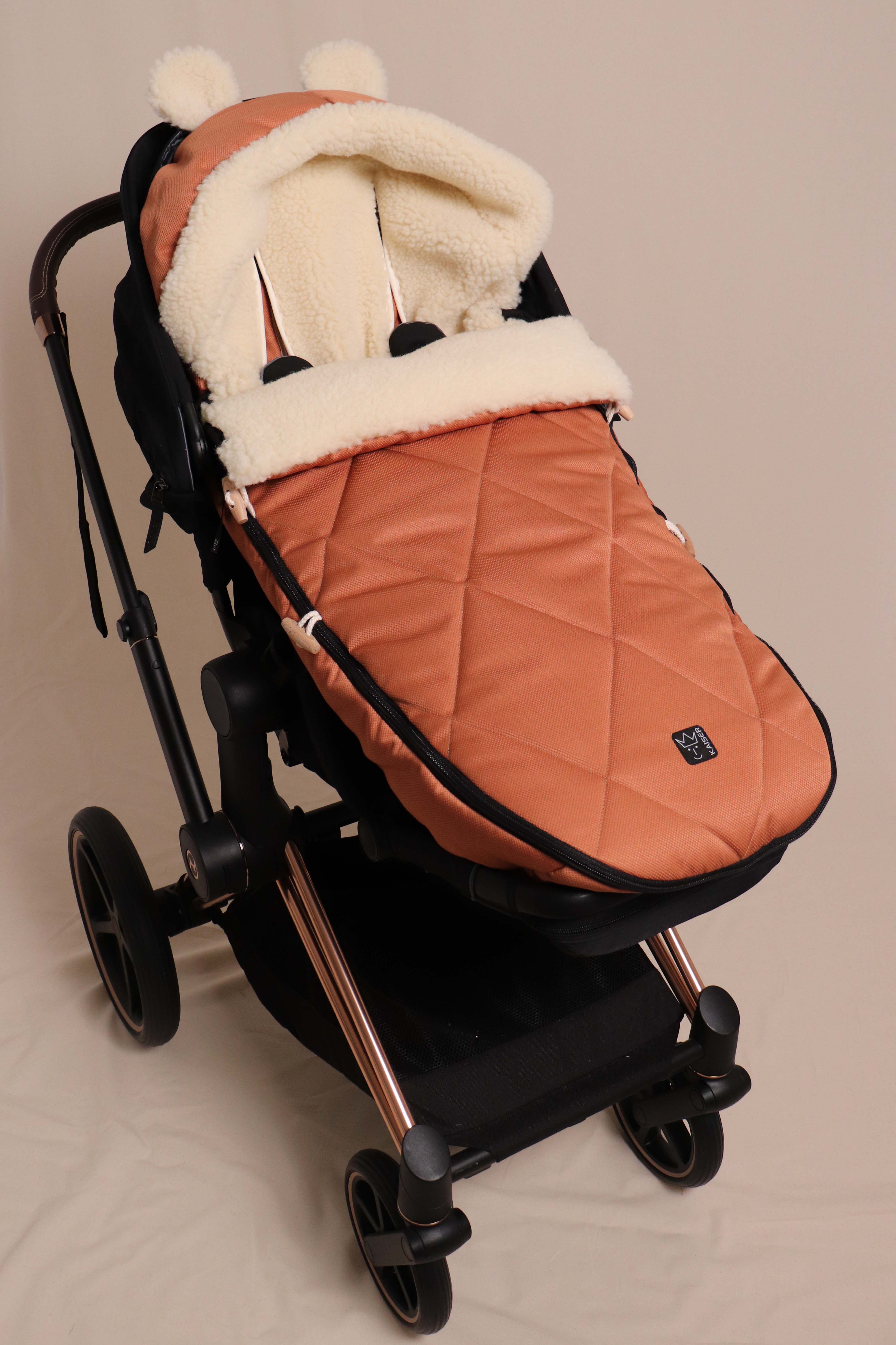 Geschlossener Fußsack in coral gold mit Schafwolle-Innenfutter ist in einem Kinderwagen eingesetzt