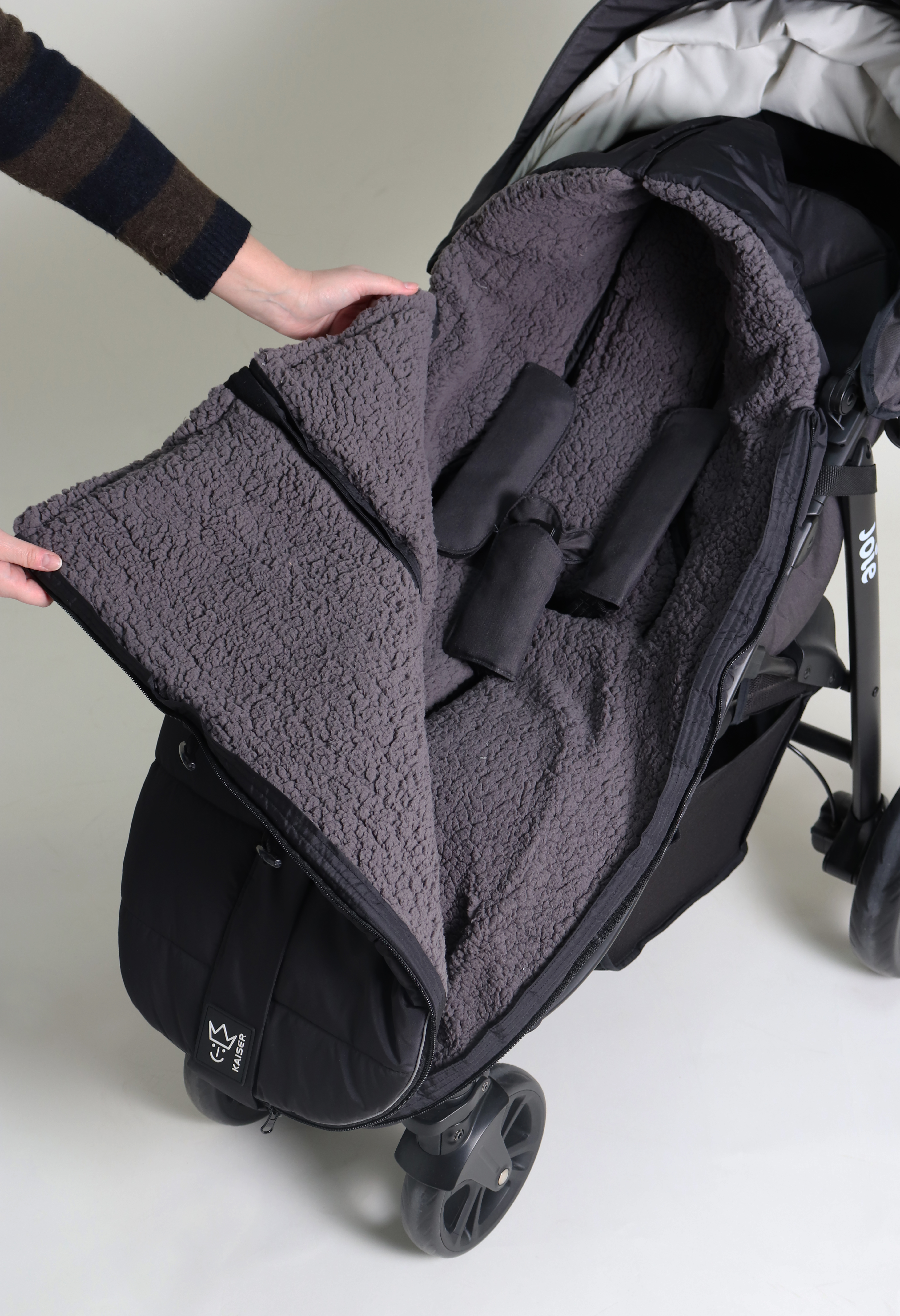 Geschlossener Fußsack mit einem Sherpa-Futter in der Farbe black ist in einem Kinderwagen eingesetzt