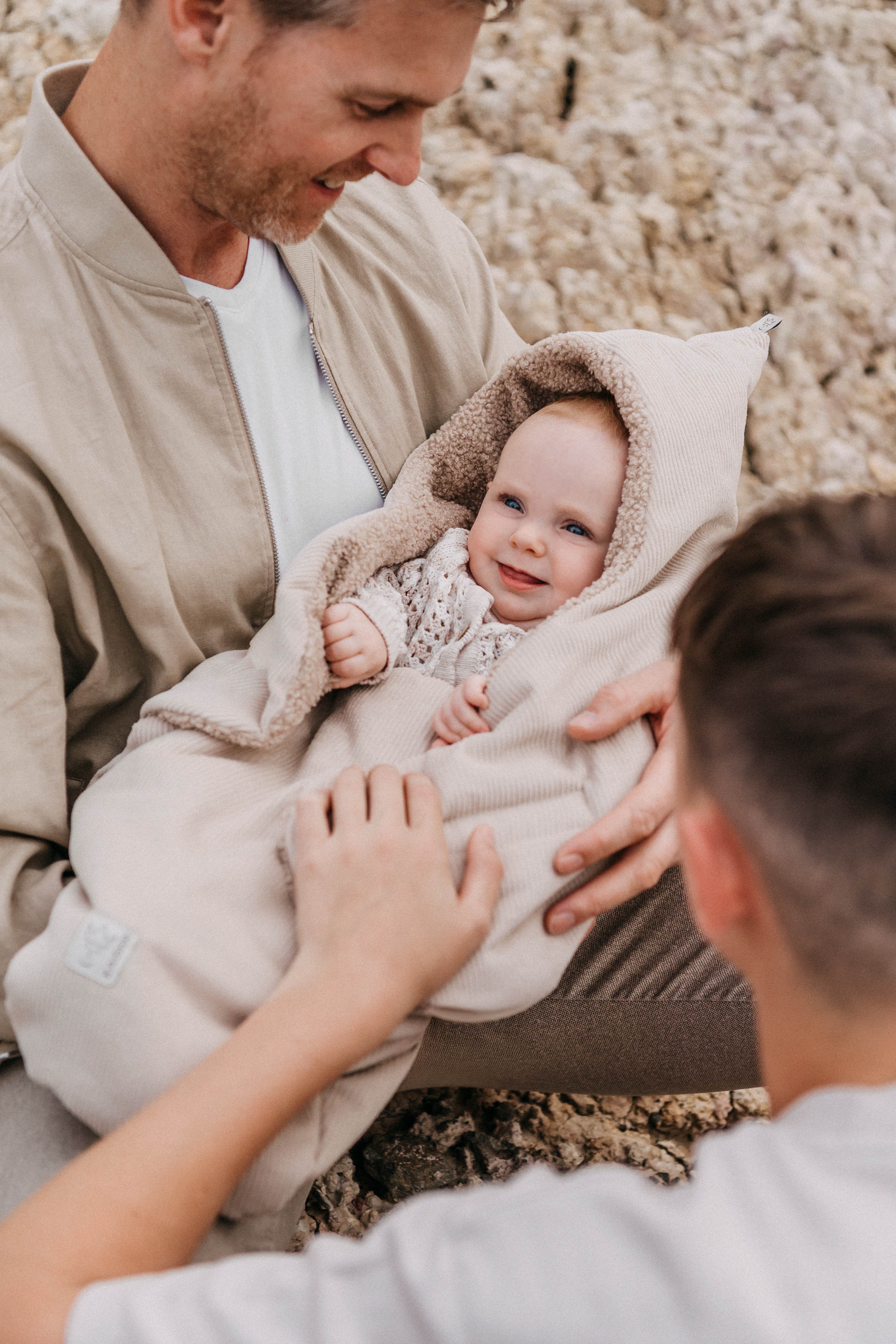 Baby in der CALLIE CORD Einschlagdecke sand shell – Outdoor Aufnahme mit Eltern
