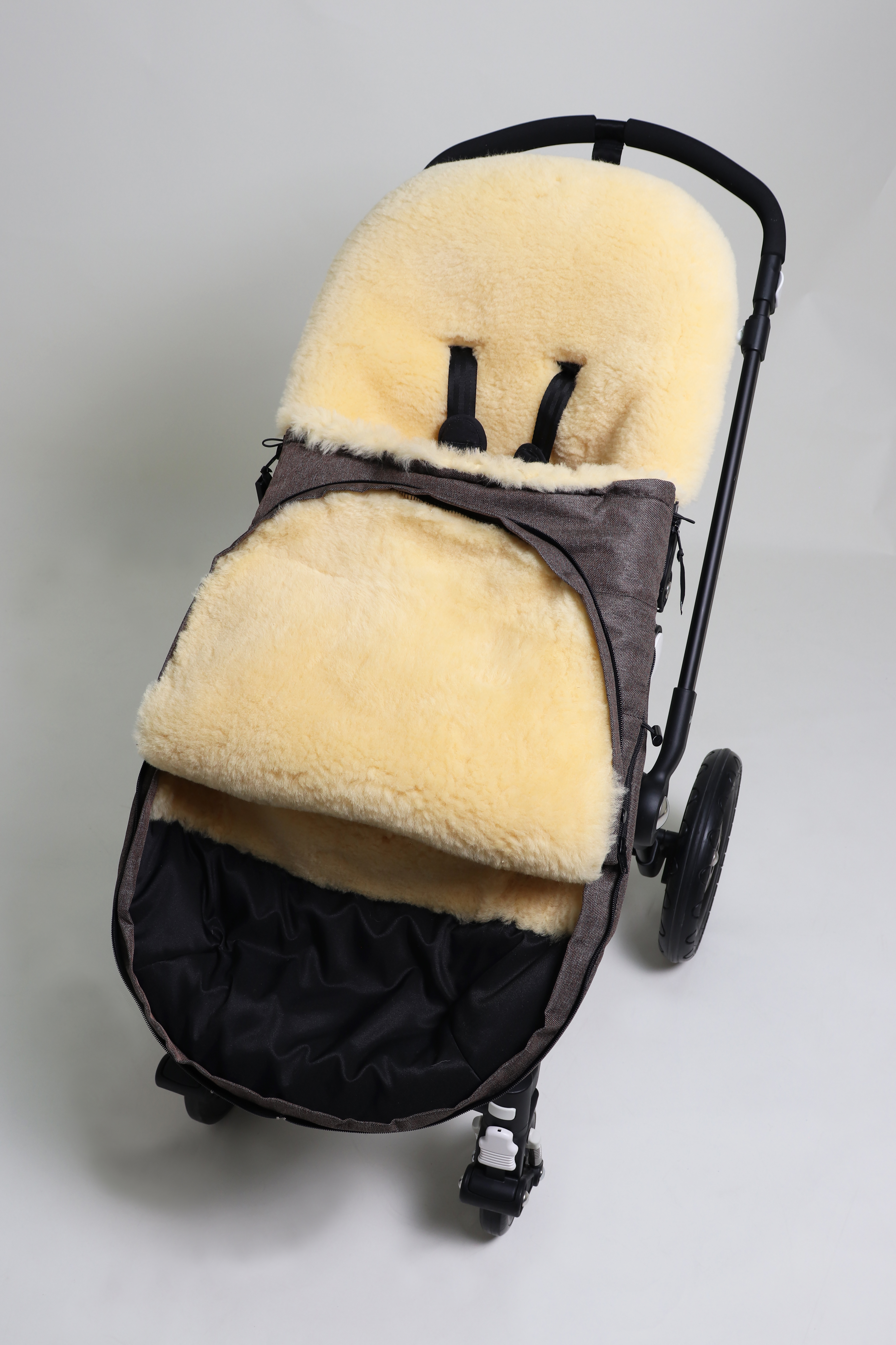 Fußsack mit dem Lammfell-Innenfutter in brown-melange in einem Kinderwagen eingesetzt