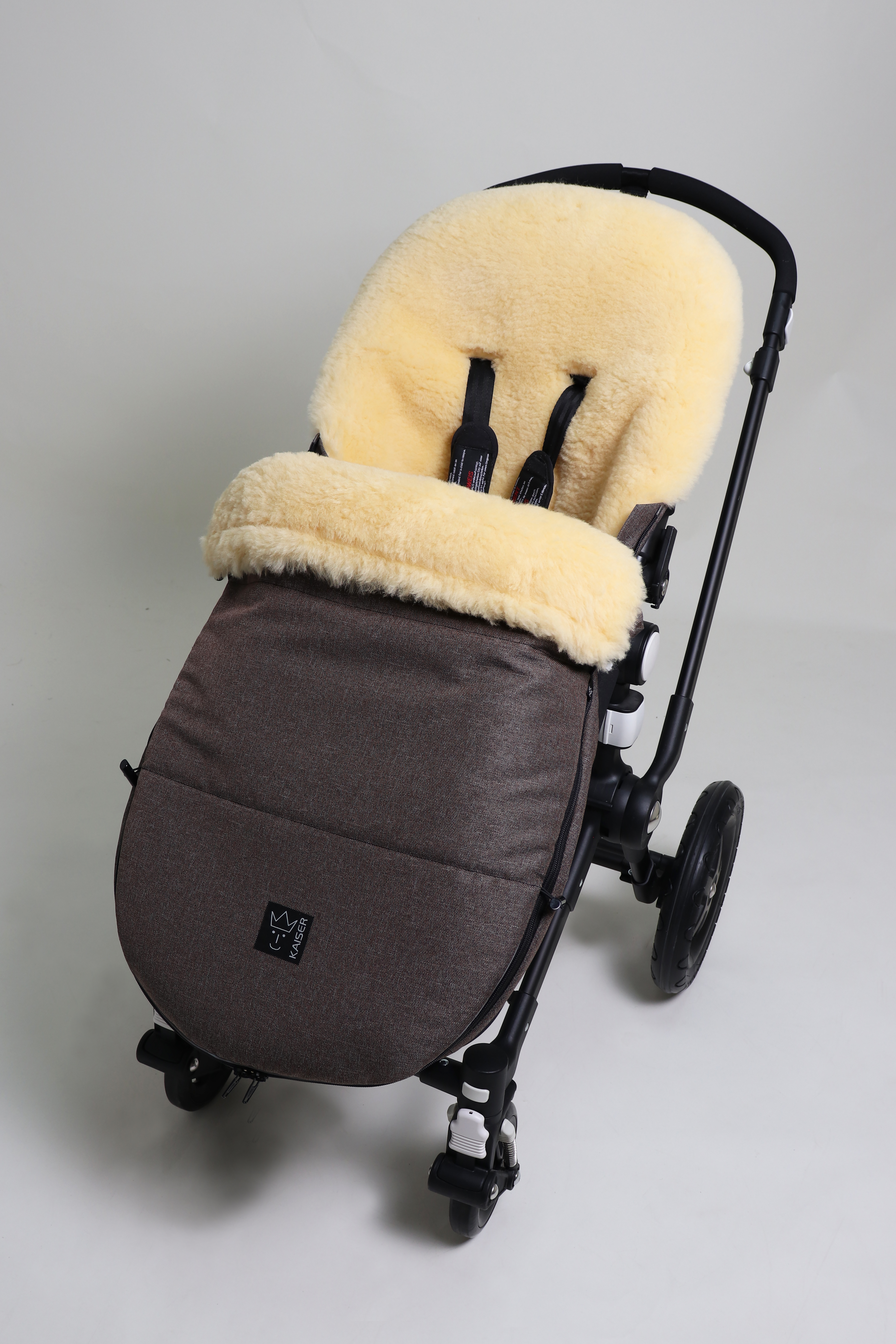 Fußsack mit dem Lammfell-Innenfutter in brown-melange in einem Kinderwagen eingesetzt
